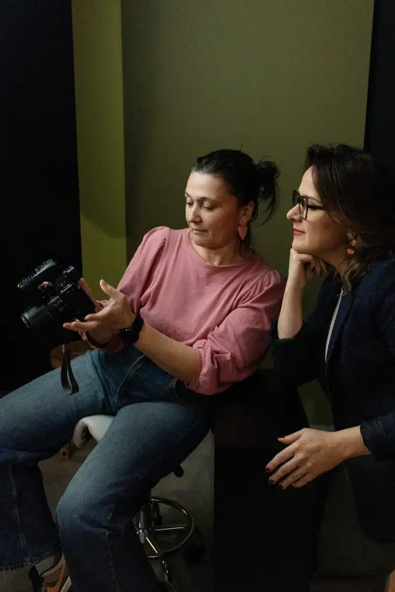 Photo de profil LinkedIn : pourquoi les photos IA ne remplaceront pas un vrai photographe, une photographe montre les photos faites d'une femme souriante en studio à sa cliente.