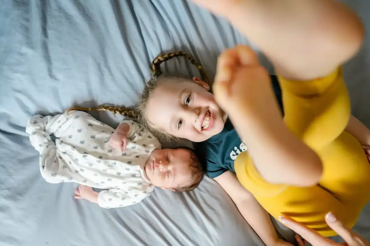 faq photographe puteaux - photo d'une grande soeur avec son petit frère sur un lit